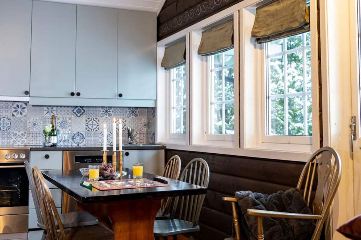 Una cocina acogedora con una mesa de madera, sillas y un horno empotrado.