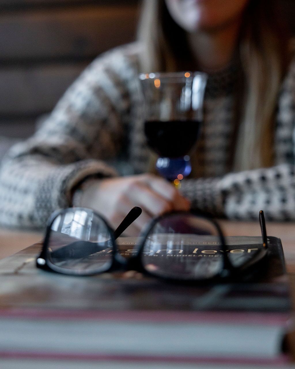 A pair of glasses on a table with a glass of red wine.