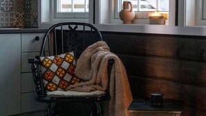 A cozy room with a patterned chair, a window with a view, and a lit candle on a table.