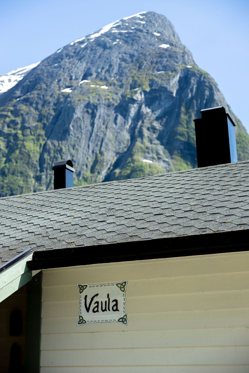 Rakennus, jonka seinässä on kyltti, jossa lukee ”Váula”, ja taustalla kohoaa vuoristo.