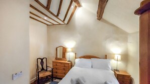 A bedroom with a wooden bed, two bedside lamps, a dresser, and a mirror.