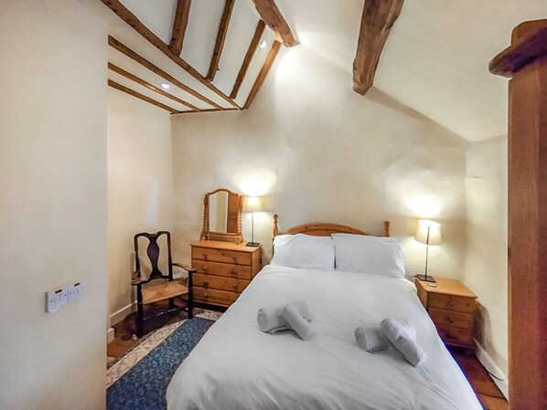 A bedroom with a wooden bed, two bedside lamps, a dresser, and a mirror.