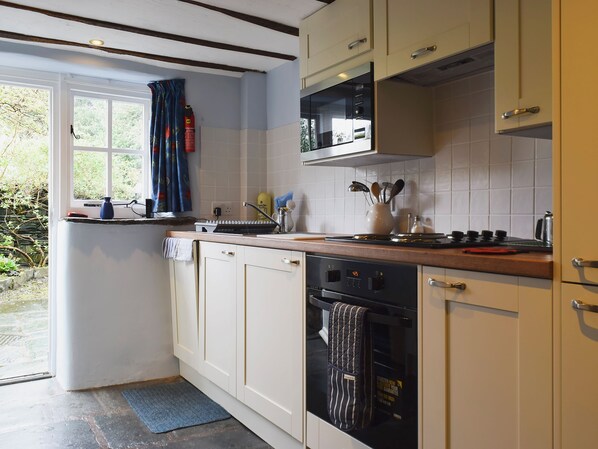 A kitchen with white cabinets, a microwave, a stove, and a dishwasher. - Traditional ’olde worlde’ cottage set in the heart of walkers paradise. (Rosthwaite)