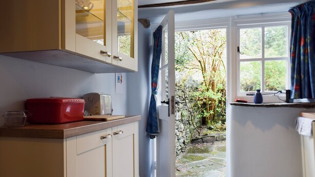 A kitchen with a toaster, a red container, and a glass cabinet.