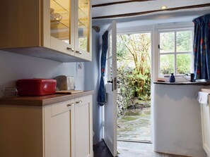A kitchen with a toaster, a red container, and a glass cabinet.