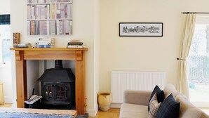 Ein gemütliches Wohnzimmer mit Kamin, einer Couch, einem Couchtisch und einem Bücherregal.