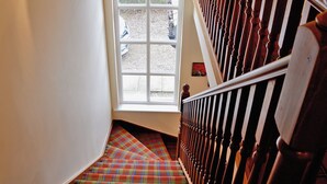 Eine Treppe mit Holzgeländer und einem Schachbrettmuster-Teppich.