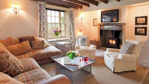 A cozy living room with a fireplace, comfortable seating, and a large window with curtains. - 5 bedroom accommodation in Kildale, near Whitby (Kildale, near Whitby)