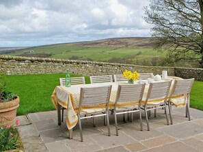 A table set outdoors with chairs, a bottle, and a vase of flowers. - 5 bedroom accommodation in Kildale, near Whitby (Kildale, near Whitby)