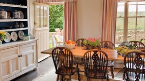 A dining area with a wooden table, chairs, and a cabinet with dishes. - 5 bedroom accommodation in Kildale, near Whitby (Kildale, near Whitby)