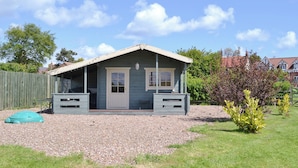 A small, single-story house with a porch, a gravel driveway, and a grassy yard. - Rockville Cottage - 24376 (Bempton, near Flamborough)