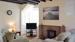 A living room with two sofas, a TV, a fireplace, and a painting on the wall. - Rockville Cottage - 24376 (Bempton, near Flamborough)