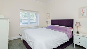 A bedroom with a bed, a nightstand, a lamp, a dresser, and a window with blinds. - 1 bedroom accommodation in Broadstairs (Broadstairs)