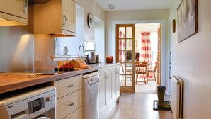A modern kitchen with a washing machine, a sink, and a dining area with a table and chairs.