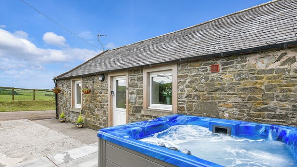 A stone building with a hot tub in front.