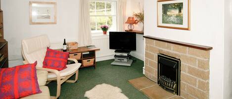 A living room with a fireplace, a television, a sofa, and a window with curtains.