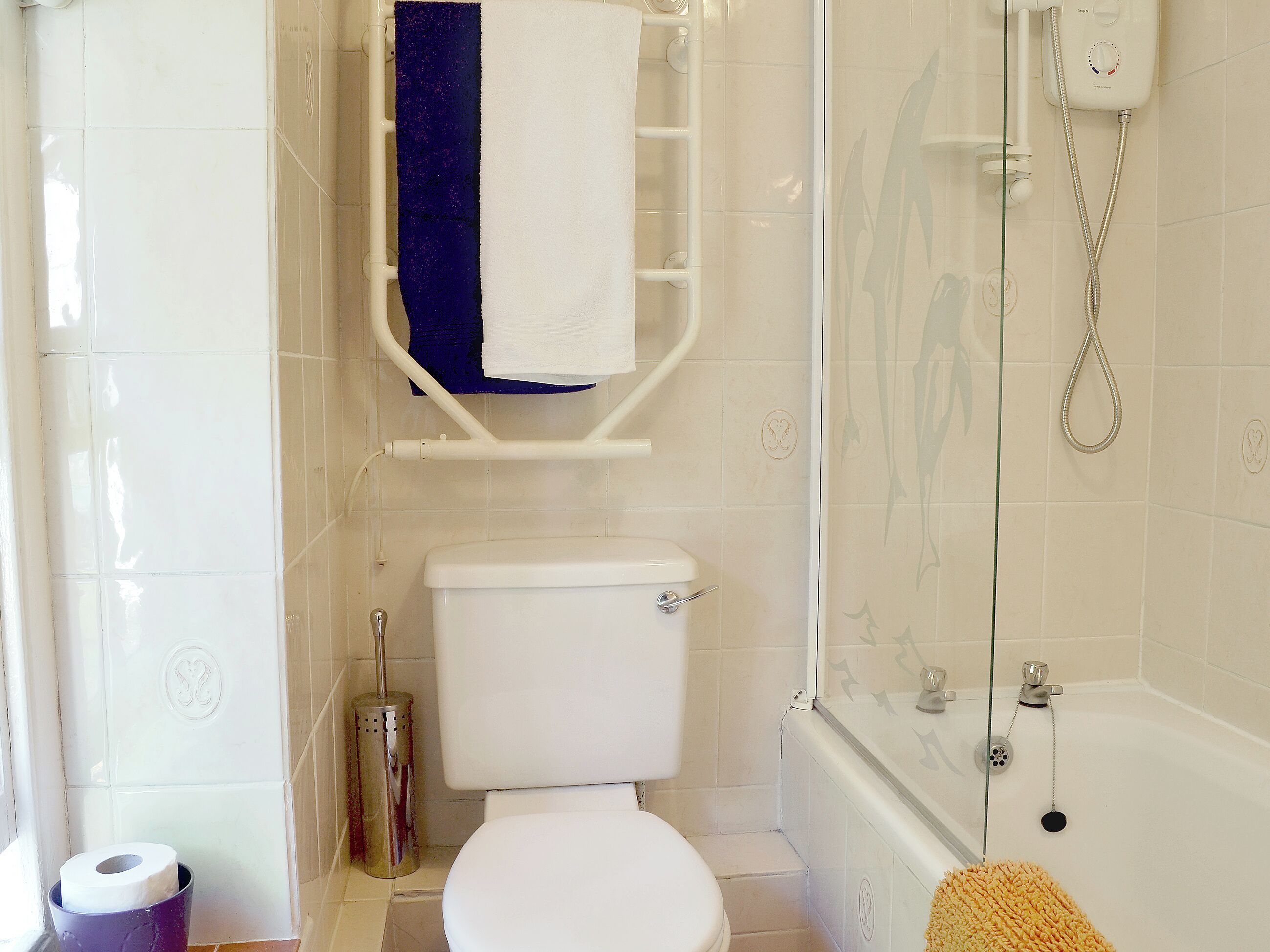 A bathroom with a toilet, a shower, and a towel rack.