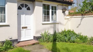 Een huis met een witte gevel, een pannendak en een voordeur met een klein raam erboven.