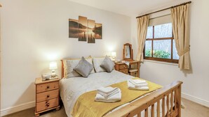 A bedroom with a bed, bedside tables, a dresser, a window with curtains, and a wall-mounted artwork.