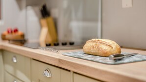 A kitchen with a loaf of bread on a cutting board, a knife, and a toaster.