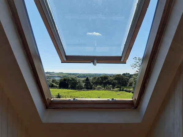 A skylight with a clear view of a green landscape and distant hills.