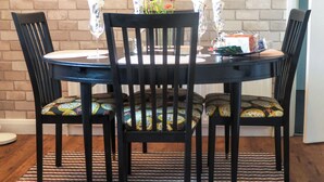 A round dining table with black chairs, each with patterned cushions.