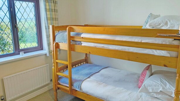 A bunk bed with a window, a radiator, and a lamp.