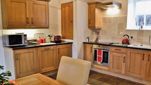 A kitchen with wooden cabinets, a microwave, a toaster, and a kettle. - Penno Cottage - 24440 (Bodmin)