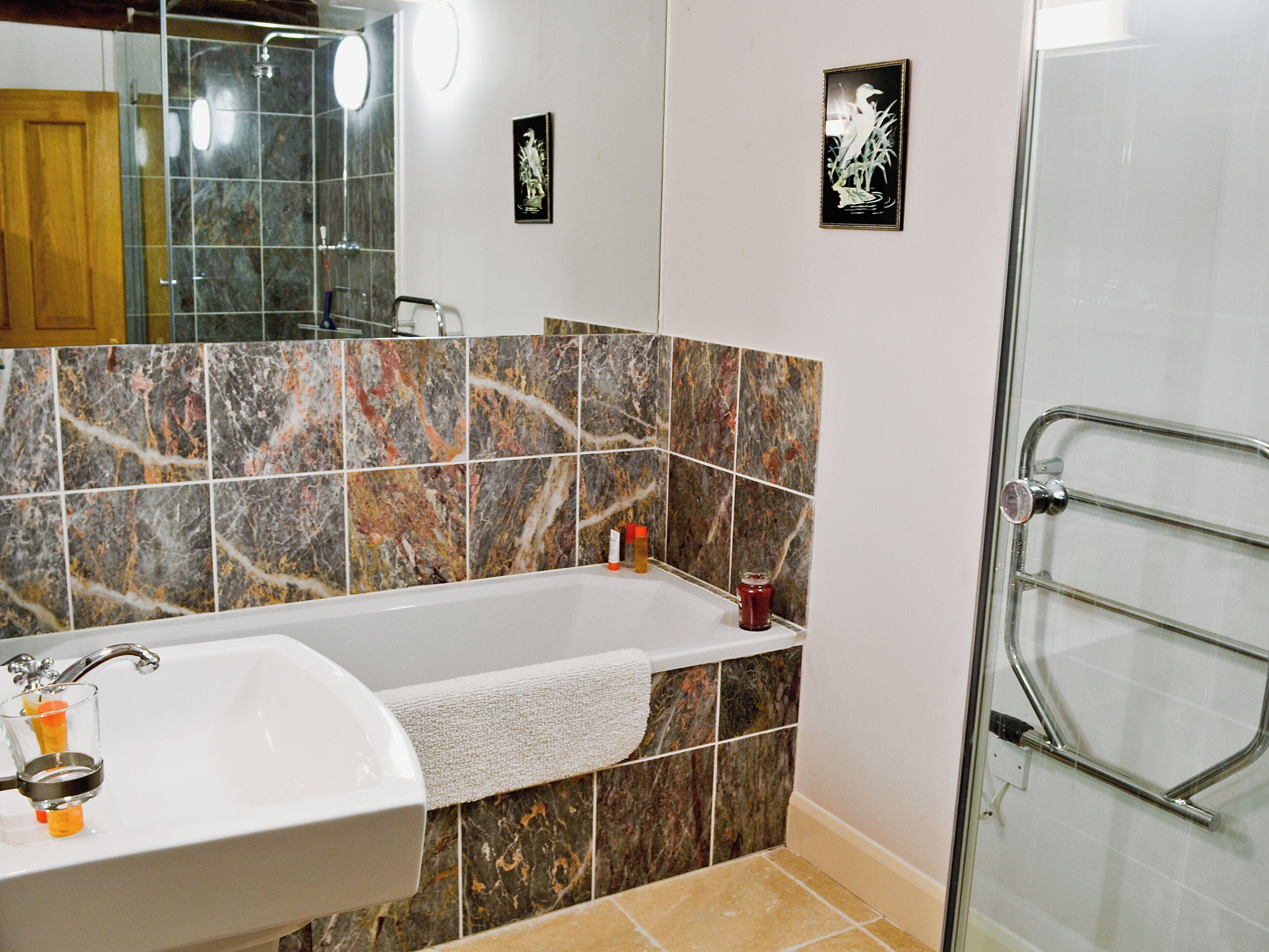 A bathroom with a bathtub, a sink, and a glass shower enclosure.