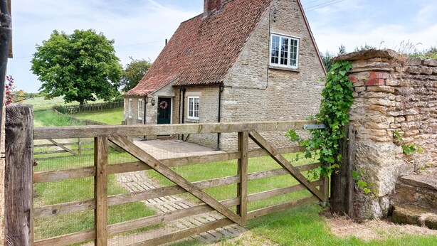 A stone house with a tiled roof, a wooden gate, and a stone wall with ivy. - Moorhouse Farm Cottage (Hovingham, near York)