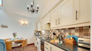 A modern kitchen with a dining area, wooden flooring, and a chandelier. - 2 bedroom accommodation in Seahouses (Seahouses)