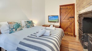 A bedroom with a bed, a television, a wooden door, and a fireplace. - 2 bedroom accommodation in Seahouses (Seahouses)