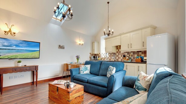 A modern living room with a sofa, coffee table, and TV. - 2 bedroom accommodation in Seahouses (Seahouses)