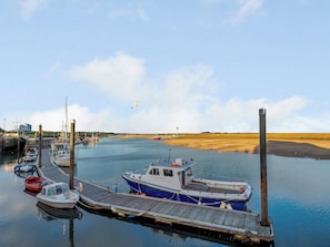 Eine Marina mit vertäuten Booten, ein hölzerner Steg und ein Sandstrand im Hintergrund.