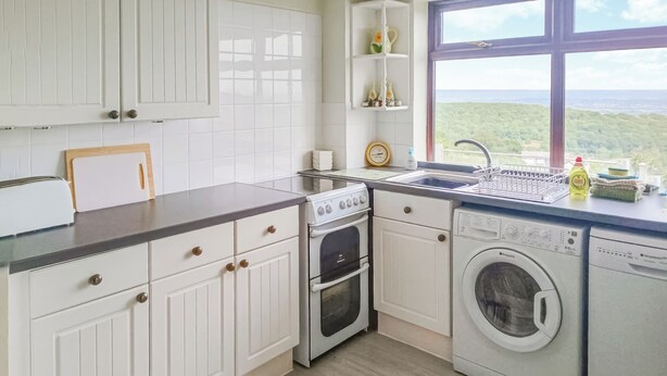 A kitchen with white cabinets, a sink, a stove, an oven, and a washing machine. - 2 bedroom accommodation in Cinderford (Cinderford)