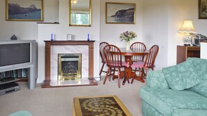 A living room with a TV, fireplace, dining table, chairs, and a sofa. - 1 bedroom accommodation in Apse Heath, near Shanklin (Apse Heath, near Shanklin)