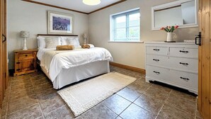 A bedroom with a bed, a nightstand, a dresser, a window with blinds, and a ceiling light fixture. - The Bran House- 23526 (Hareby, near Horncastle)