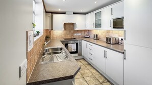 A modern kitchen with white cabinets, a granite countertop, a stainless steel sink, and a microwave. - The Bran House- 23526 (Hareby, near Horncastle)