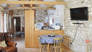 Ein rustikales Interieur mit einem Holzespeisetisch, Stühlen, einem Ledersessel, einer Küchenzeile und einem Wand-Fernseher.