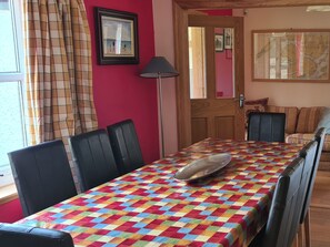 A dining area with a checkered tablecloth, black chairs, a lamp, and a map on the wall.