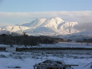 A snowy landscape with a mountain in the background, a stone wall, and a pile of firewood. - 3 bedroom accommodation in Ardgour, near Fort William (Ardgour, near Fort William)