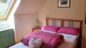 A bedroom with a sloped ceiling, a bed with pink bedding, a heart-shaped pillow, a bedside table with a lamp, and a framed picture on the wall. - 3 bedroom accommodation in Ardgour, near Fort William (Ardgour, near Fort William)