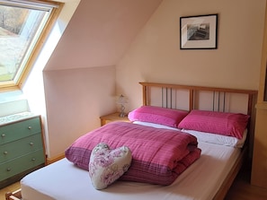 A bedroom with a sloped ceiling, a bed with pink bedding, a heart-shaped pillow, a bedside table with a lamp, and a framed picture on the wall. - 3 bedroom accommodation in Ardgour, near Fort William (Ardgour, near Fort William)