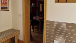 A room with a wooden door, a bench, a tiled wall, and a framed poster on the wall. - 3 bedroom accommodation in Ardgour, near Fort William (Ardgour, near Fort William)