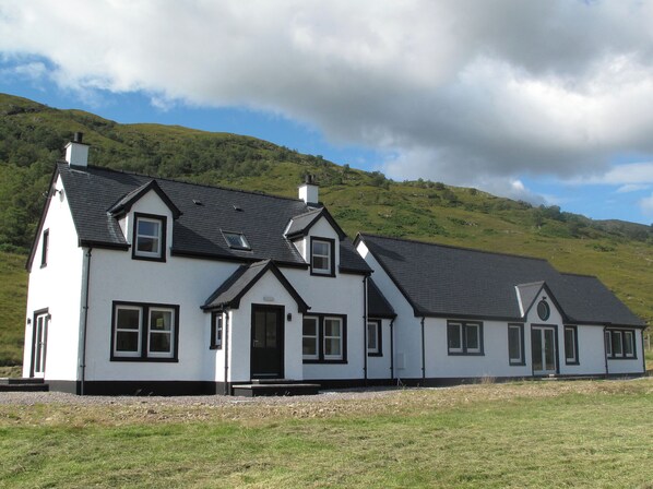 A two-story white house with a black roof, multiple windows, and a chimney. - 3 bedroom accommodation in Ardgour, near Fort William (Ardgour, near Fort William)