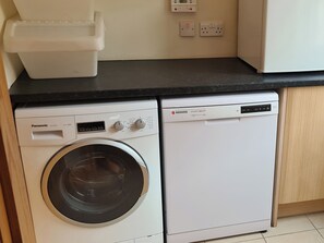A compact laundry area with a front-loading washing machine and a stacked dryer.