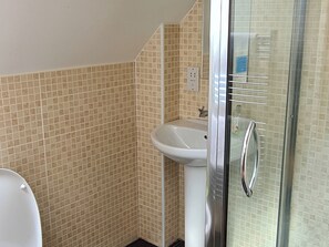 A bathroom with beige tiled walls, a white sink, and a glass shower enclosure. - 3 bedroom accommodation in Ardgour, near Fort William (Ardgour, near Fort William)