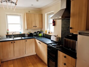 A kitchen with wooden cabinets, a black countertop, a stove, and a refrigerator.