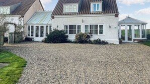 A two-story house with a gravel driveway, a conservatory, and a glass-roofed gazebo. - 1 bedroom accommodation in Stalham (Stalham)