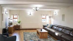A living room with a sofa, a coffee table, a TV, and a fireplace. - Characterful, rural barn conversion. (Heathcote, near Hartington)